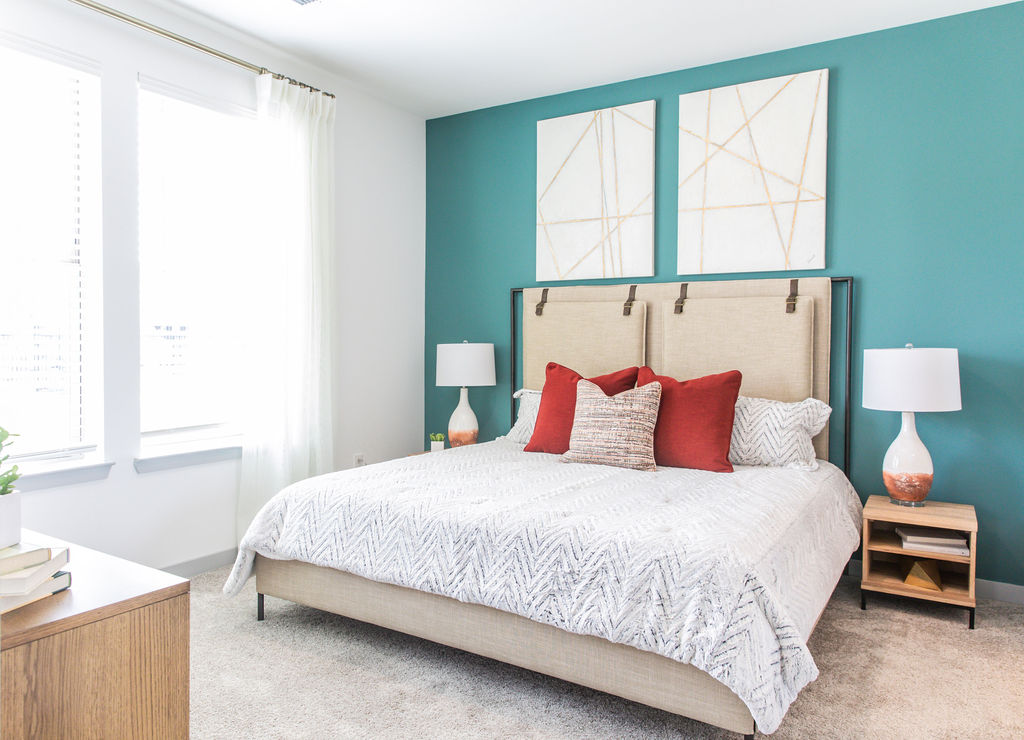 One-BR Apartments in Birmingham AL - Estelle Birmingham - Furnished Bedroom with Plush Carpeted Floors, Teal Accent Wall, and Two Windows